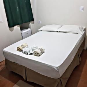 ein Bett mit weißer Bettwäsche und Handtüchern darauf in der Unterkunft Pousada Descanso de Casa in João Pessoa