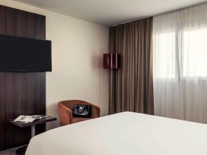 Zimmer mit einem Bett, einem Stuhl und einem Fenster in der Unterkunft Mercure Paris Porte d'Orleans in Montrouge