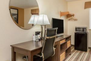 a room with a desk with a television and a chair at Super 8 by Wyndham Latham - Albany Airport in Latham