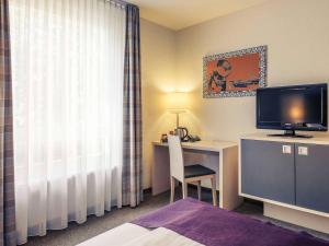 a hotel room with a television and a bed at Mercure Hotel Berlin City West in Berlin