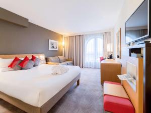 um quarto de hotel com uma cama grande e um sofá em Novotel Southampton em Southampton