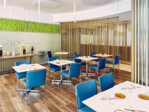una sala da pranzo con tavoli bianchi e sedie blu di Novotel Venezia Mestre Castellana a Mestre
