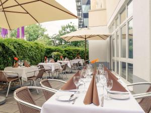 Mercure Neu-Isenburg في نيو ايسنبرغ: مطعم به طاولات وكراسي ومظلات