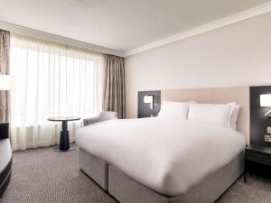 a large white bed in a hotel room at Sofitel London Gatwick in Horley