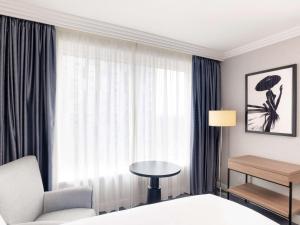 um quarto de hotel com uma cama, uma mesa e uma janela em Sofitel London Gatwick em Horley