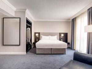a hotel room with a bed and a mirror at Sofitel London Gatwick in Horley