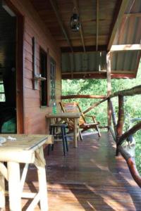 um alpendre de uma cabina com uma mesa e bancos em Treehouse Holidays-Lake View em Ko Yao Noi