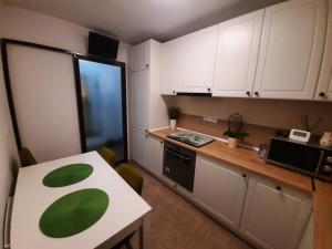 a kitchen with white cabinets and a table with a green leaf on it at Happy apartament in Sibiu