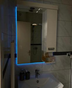 baño con lavabo y espejo con luces azules en Stan na dan Bella, en Banja Luka