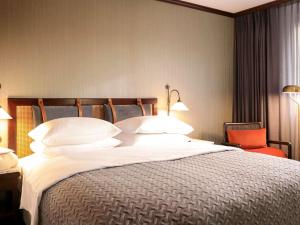 a bedroom with a large bed with white pillows at Mercure Hotel Frankfurt Airport Langen in Langen