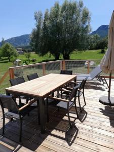 uma mesa de madeira com cadeiras e um guarda-sol num deque em La Maison de Toi et Moi em Castellane