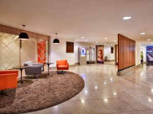 a lobby with orange chairs and a circular rug at Mercure Rio de Janeiro Barra da Tijuca in Rio de Janeiro