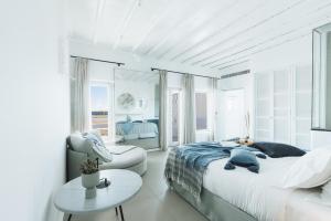 a white bedroom with a large bed and a table at Mykonos Blanc - Preferred Hotels & Resorts in Ornos +37 photos