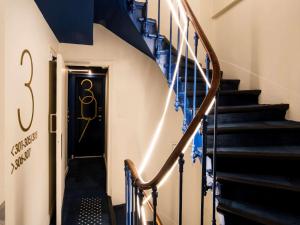 a stairway with a black door and blue stairs at ibis Styles Paris Opera Lafayette in Paris