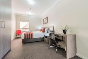 シドニーにあるBest Western Plus Camperdown Suitesのベッド、デスク、椅子が備わるホテルルームです。
