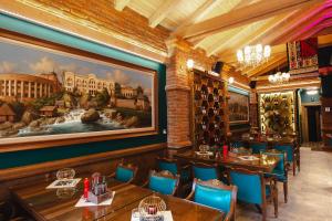 a dining room with tables and chairs and a painting on the wall at Hotel Integra Banja Luka in Banja Luka
