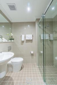 y baño con aseo, lavabo y ducha. en Best Western Plus Camperdown Suites en Sídney