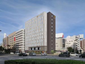 a tall building with cars parked in a parking lot at Comfort Hotel Takamatsu in Takamatsu