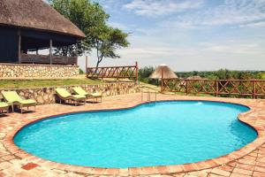 duży basen z krzesłami i budynek w obiekcie Twiga Safari Lodge w mieście Murchison Falls National Park