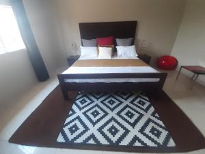 a bedroom with a large bed and a rug at Halina's Apartment in Lusaka