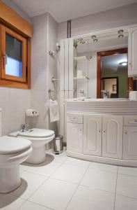 a white bathroom with a toilet and a sink at Apartamento de La Casona de Riomera in Oviedo