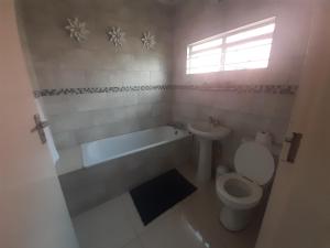 a bathroom with a toilet and a tub and a sink at Halina's Apartment in Lusaka