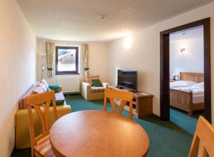 ein Hotelzimmer mit einem Tisch und einem Wohnzimmer in der Unterkunft Ferienwohnungen Hirschen in Bichlbach