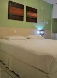 a large white bed in a room with two paintings on the wall at Quarto em Gran Lençóis Flat Residence in Barreirinhas