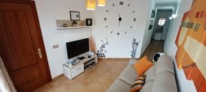 a living room with a couch and a clock on the wall at Vivienda vacacional in Puerto del Rosario