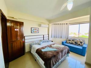 a bedroom with a bed and a blue couch at Apart-Hotel Pacífico in Tramandaí