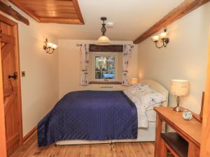 a bedroom with a bed with a blue comforter and a window at The Cobbles in Penrith