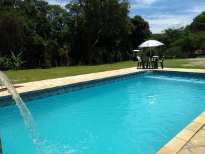 uma piscina com um guarda-sol, uma mesa e cadeiras em Pousada Erva Doce em Monte Alegre do Sul