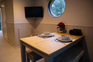 a dining room table with two cups and a tv at Lady Florence, Maidstone a Unique River Boat with Castle Views in Kent