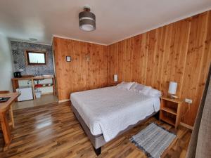 1 dormitorio con 1 cama y pared de madera en Apart Hotel Antu de Villarrica, en Villarrica