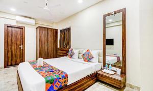 a bedroom with a large bed and a mirror at FabHotel Carnival in Kolkata