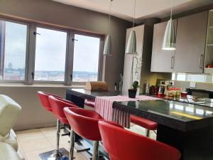 una cocina con sillas rojas y una barra con ventanas en Franklin Luxury Apartment, en Johannesburgo