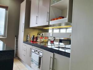 uma cozinha com armários brancos e um balcão preto em Franklin Luxury Apartment em Joanesburgo