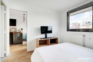 Un dormitorio blanco con una cama y un televisor. en Cozy apartment - 1BR-4P - next to Paris, en Levallois-Perret