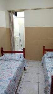 two beds in a room with a window at Hotel Brasil in Presidente Prudente
