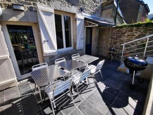 a patio with a table and chairs and a grill at La Bayenne in Revin