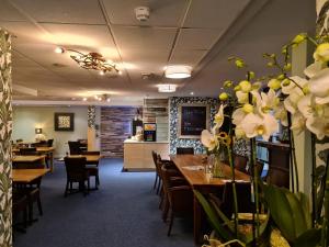 a dining room with tables and chairs and flowers at Amsterdam Hotel Uithoorn in Uithoorn