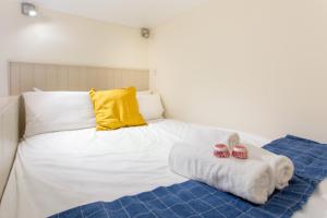 a white bed with a yellow pillow and two towels at ALTIDO Haymarket in Edinburgh