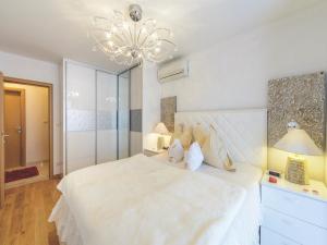 a bedroom with a large white bed with a chandelier at Apartment Viva la Vita in Cavtat