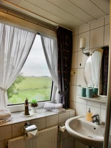 a bathroom with a sink and a window at Landhotel Bauernstuben in Neuharlingersiel
