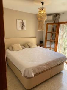 a bedroom with a large white bed with a chandelier at Villa Francisco in Calonge +11 photos