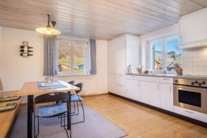 a kitchen with white cabinets and a table with chairs at Wohnung Kanisfluhblick in Bizau