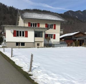 a house with red windows in a snow covered yard at Wohnung Kanisfluhblick in Bizau +16 photos