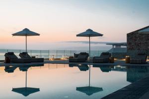 a group of chairs and umbrellas sitting next to a pool at Aliv stone suites & spa in Agios Nikolaos