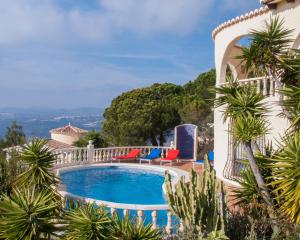 a villa with a swimming pool and palm trees at Casa Inca, Villa with heatable pool and top view atop Moraira El Portet in Cumbre del Sol