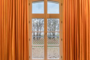 an open window with orange curtains in a room at Jagdschloß zu Hohen Niendorf in Hohen Niendorf